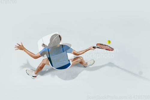 Image of Young woman in blue shirt playing tennis. Youth, flexibility, power and energy.