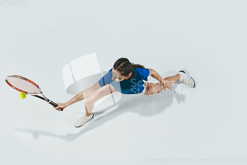 Image of Young woman in blue shirt playing tennis. Youth, flexibility, power and energy.