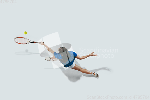 Image of Young woman in blue shirt playing tennis. Youth, flexibility, power and energy.