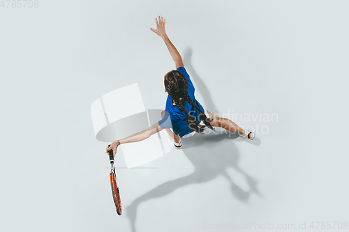 Image of Young woman in blue shirt playing tennis. Youth, flexibility, power and energy.