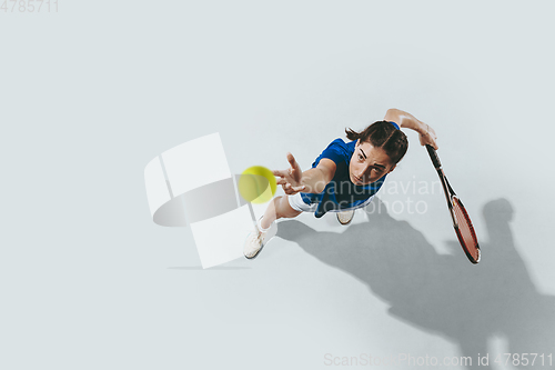 Image of Young woman in blue shirt playing tennis. Youth, flexibility, power and energy.