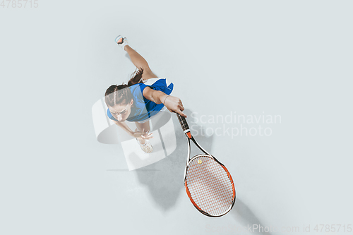 Image of Young woman in blue shirt playing tennis. Youth, flexibility, power and energy.