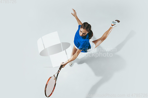 Image of Young woman in blue shirt playing tennis. Youth, flexibility, power and energy.