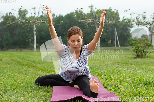 Image of Young beautiful woman doing yoga exercise in green park. Healthy lifestyle and fitness concept.