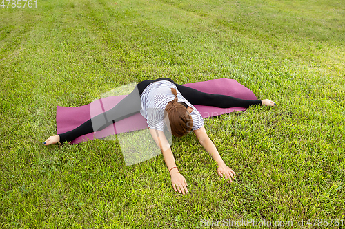 Image of Young beautiful woman doing yoga exercise in green park. Healthy lifestyle and fitness concept.