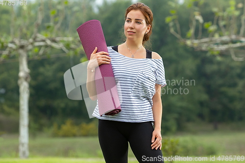 Image of Young beautiful woman doing yoga exercise in green park. Healthy lifestyle and fitness concept.