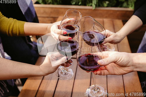 Image of People clinking glasses with wine on the summer terrace of cafe or restaurant. Close up shot, lifestyle.