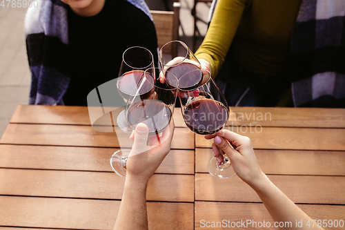 Image of People clinking glasses with wine on the summer terrace of cafe or restaurant. Close up shot, lifestyle.