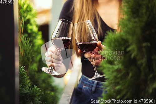 Image of People clinking glasses with wine on the summer terrace of cafe or restaurant. Close up shot, lifestyle.