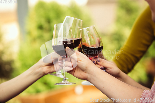 Image of People clinking glasses with wine on the summer terrace of cafe or restaurant. Close up shot, lifestyle.