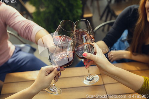 Image of People clinking glasses with wine on the summer terrace of cafe or restaurant. Close up shot, lifestyle.