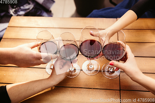 Image of People clinking glasses with wine on the summer terrace of cafe or restaurant. Close up shot, lifestyle.