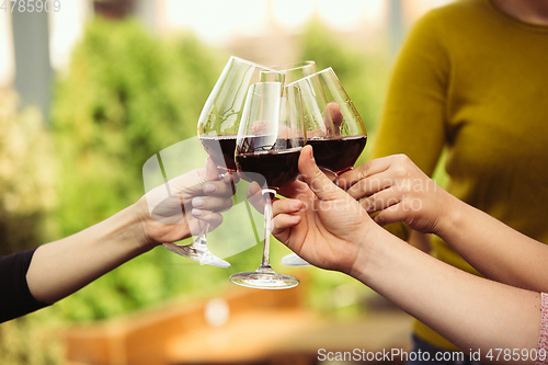 Image of People clinking glasses with wine on the summer terrace of cafe or restaurant. Close up shot, lifestyle.