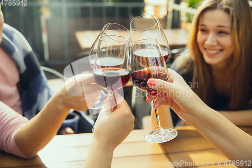 Image of People clinking glasses with wine on the summer terrace of cafe or restaurant. Close up shot, lifestyle.