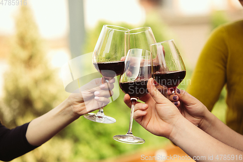 Image of People clinking glasses with wine on the summer terrace of cafe or restaurant. Close up shot, lifestyle.