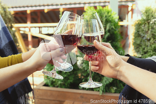 Image of People clinking glasses with wine on the summer terrace of cafe or restaurant. Close up shot, lifestyle.