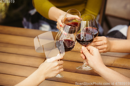 Image of People clinking glasses with wine on the summer terrace of cafe or restaurant. Close up shot, lifestyle.