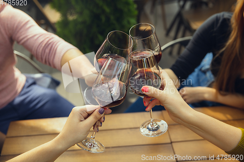 Image of People clinking glasses with wine on the summer terrace of cafe or restaurant. Close up shot, lifestyle.