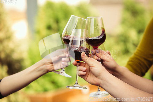 Image of People clinking glasses with wine on the summer terrace of cafe or restaurant. Close up shot, lifestyle.