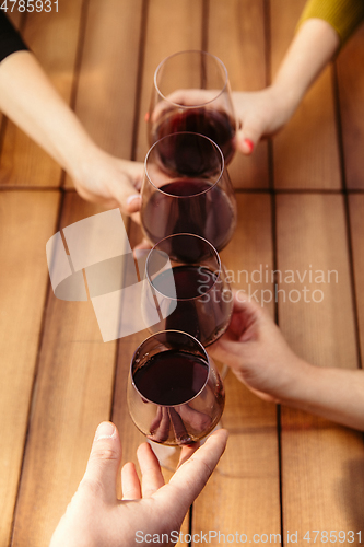 Image of People clinking glasses with wine on the summer terrace of cafe or restaurant. Close up shot, lifestyle.