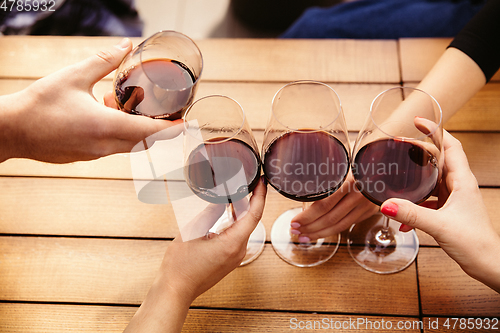 Image of People clinking glasses with wine on the summer terrace of cafe or restaurant. Close up shot, lifestyle.