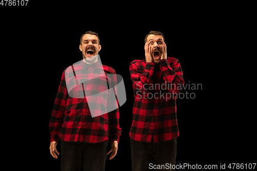 Image of Young handsome man arguing with himself on black studio background.