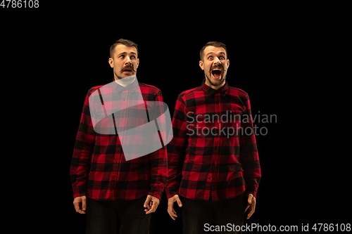 Image of Young handsome man arguing with himself on black studio background.