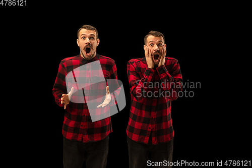 Image of Young handsome man arguing with himself on black studio background.