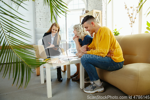 Image of Interior designer working with young couple. Lovely family and professional designer or architector.