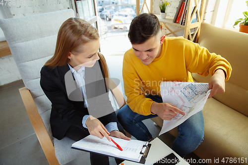 Image of Interior designer working with young couple. Lovely family and professional designer or architector.