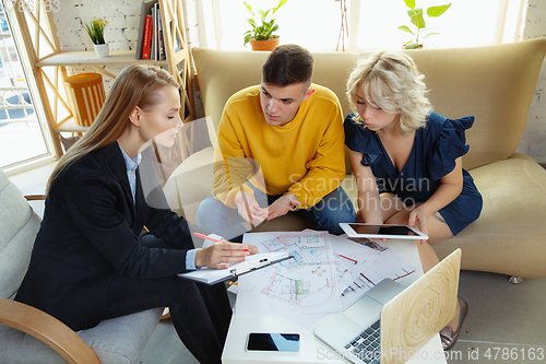 Image of Interior designer working with young couple. Lovely family and professional designer or architector.