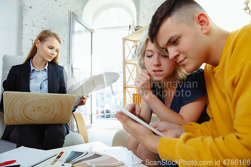 Image of Interior designer working with young couple. Lovely family and professional designer or architector.