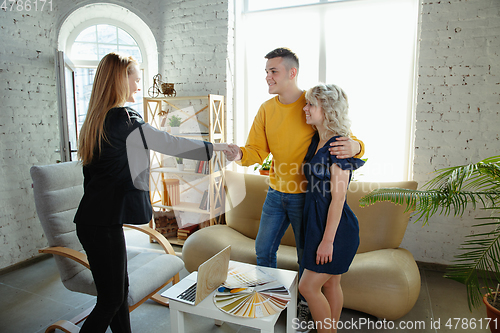 Image of Interior designer working with young couple. Lovely family and professional designer or architector.