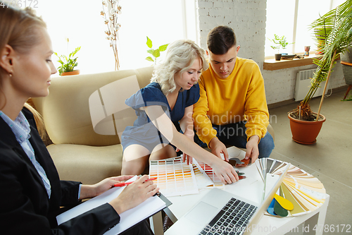 Image of Interior designer working with young couple. Lovely family and professional designer or architector.