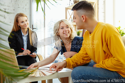 Image of Interior designer working with young couple. Lovely family and professional designer or architector.