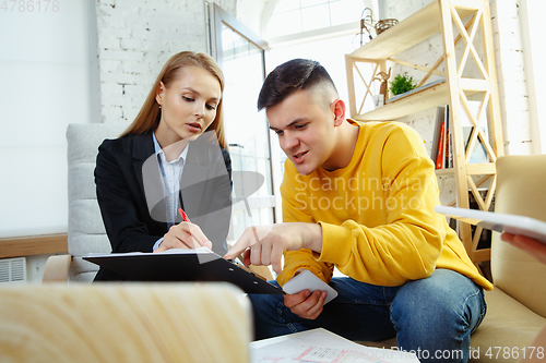 Image of Interior designer working with young couple. Lovely family and professional designer or architector.