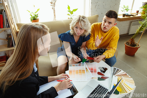 Image of Interior designer working with young couple. Lovely family and professional designer or architector.