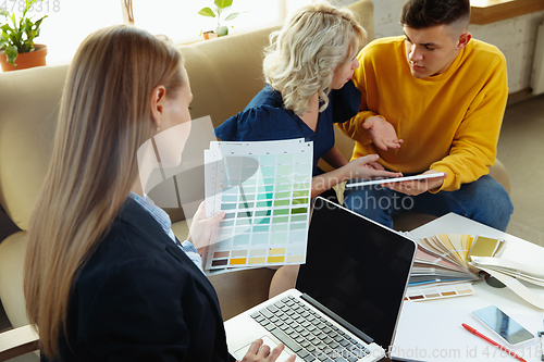 Image of Interior designer working with young couple. Lovely family and professional designer or architector.