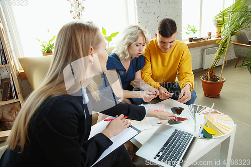 Image of Interior designer working with young couple. Lovely family and professional designer or architector.