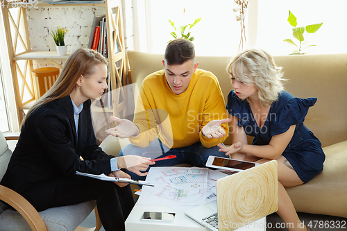 Image of Interior designer working with young couple. Lovely family and professional designer or architector.