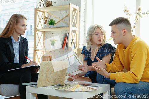 Image of Interior designer working with young couple. Lovely family and professional designer or architector.