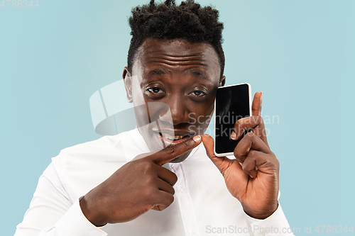 Image of Young african-american man isolated on blue studio background, human emotions concept.