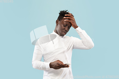 Image of Young african-american man isolated on blue studio background, human emotions concept.