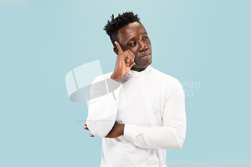 Image of Young african-american man isolated on blue studio background, human emotions concept.