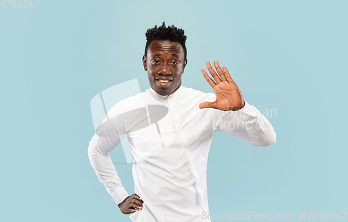 Image of Young african-american man isolated on blue studio background, human emotions concept.