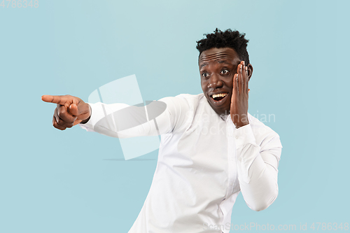 Image of Young african-american man isolated on blue studio background, human emotions concept.