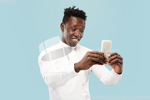 Image of Young african-american man isolated on blue studio background, human emotions concept.