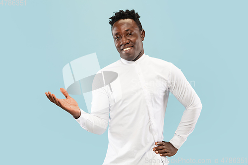 Image of Young african-american man isolated on blue studio background, human emotions concept.