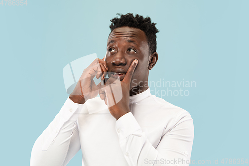 Image of Young african-american man isolated on blue studio background, human emotions concept.