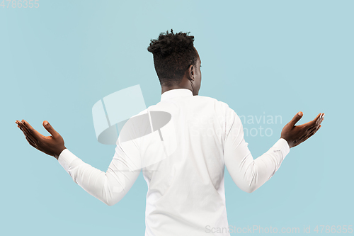 Image of Young african-american man isolated on blue studio background, human emotions concept.